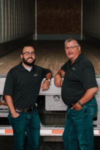 Strick employees in front of an empty semi trailer