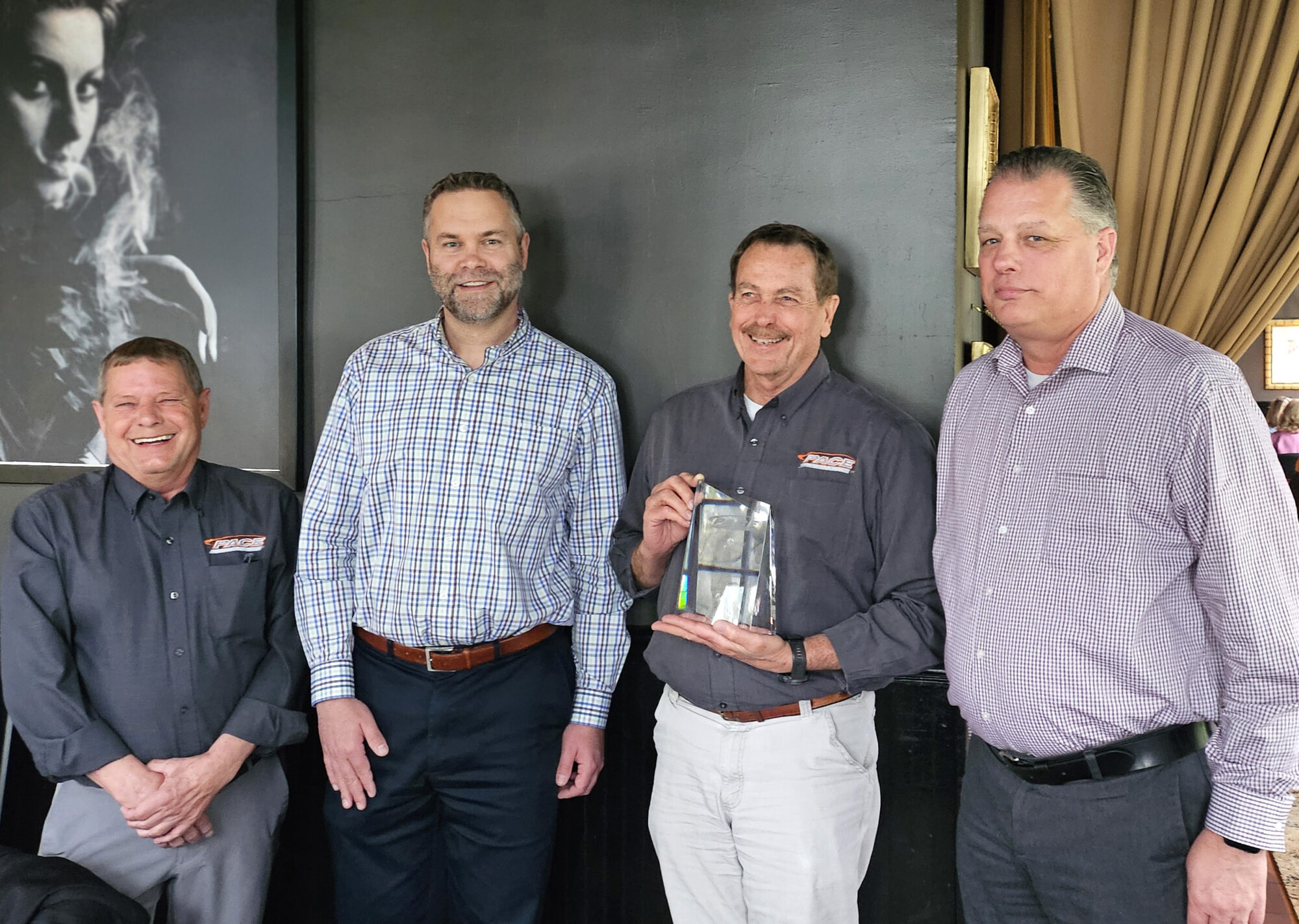 Four men standing together and holding a crystal award.