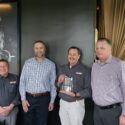 Four men standing together and holding a crystal award.