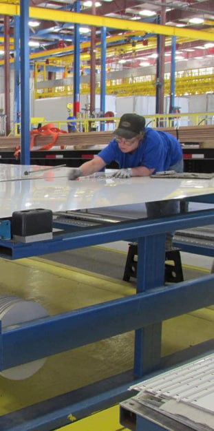 Woman in blue shirt working on manufacturing floor.